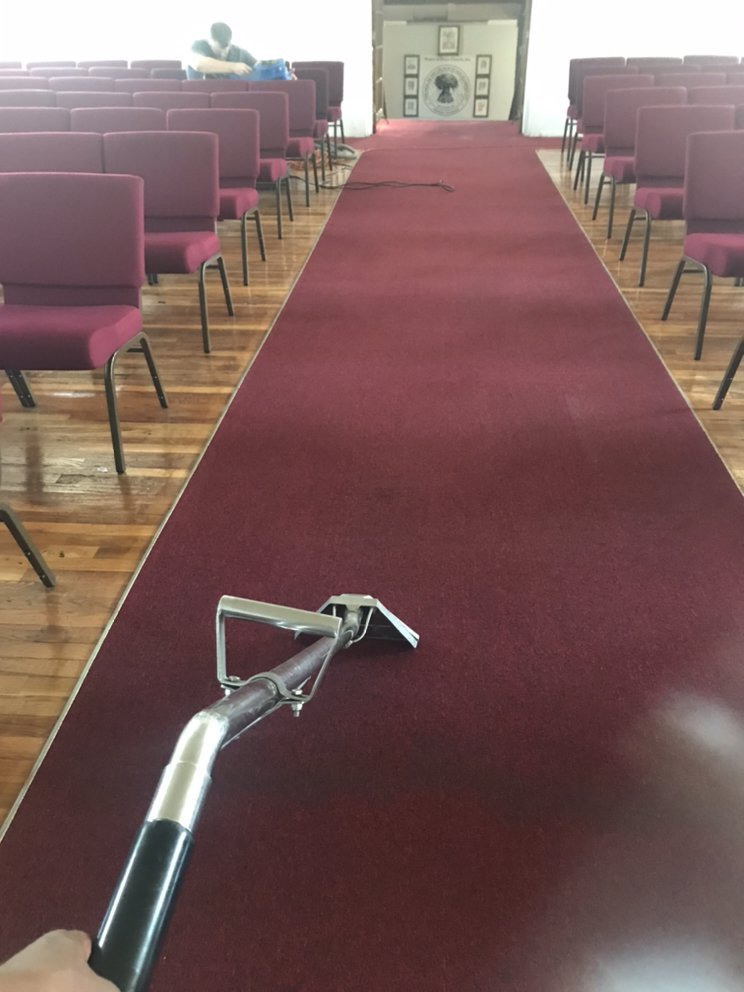 A professional cleaner cleaned the red carpet using a vacuum cleaner.