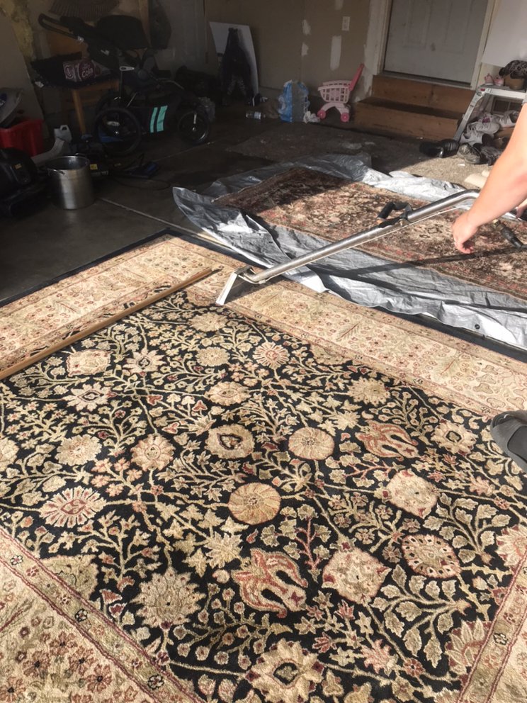 A man cleaned a big carpet with unique design.